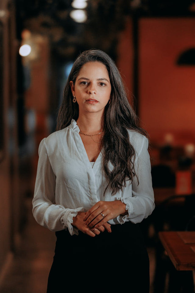 A woman with long dark hair, standing in a warmly lit salon